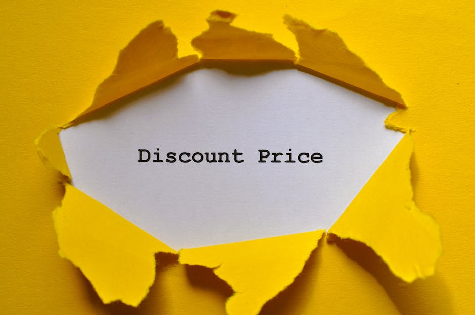 A sheet of white paper with the words 'Discount Price' printed in black text is visible through a jagged tear in a yellow paper surface. The torn yellow paper surrounds the white sheet, with uneven, r